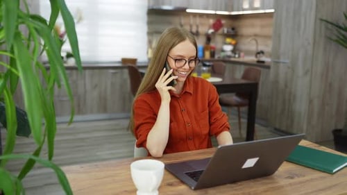 Woman with Laptop Talking on Phone at Home