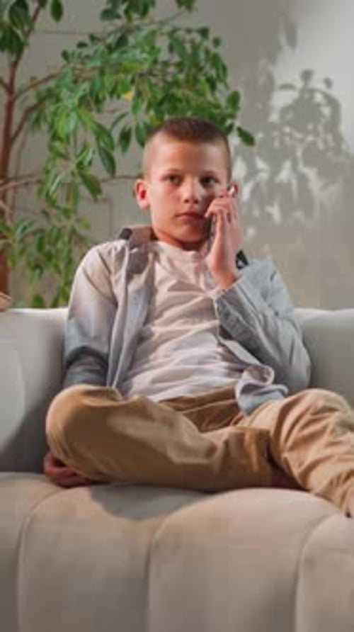 Boy Smiles Listening to Friend Talking on Phone After School