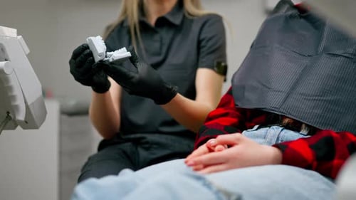 Close Up Dental Office Brunette Dentist in a Black Uniform Consults a Girl Showing a Dental Cast