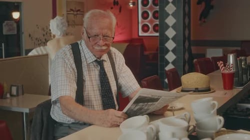 Portrait of Senior Man with Newspaper in 1980s Style Diner