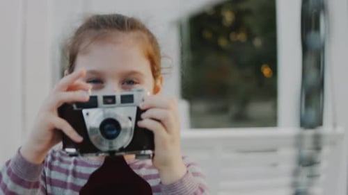 A Cute Little School Girl Takes Her First Pictures of Nature with a Retro Camera Making First Steps