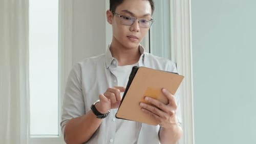 Young Adult Using Tablet by Window Indoors