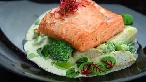 Salmon dish served on a plate with vegetables and sauce in a restaurant setting.