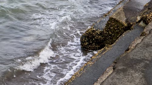 A close-up handheld shot of waves crashing against the stairs of a pier on a lake in Auckland, New Z