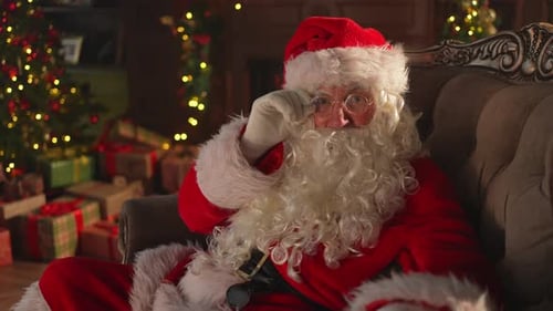 Santa Claus Resting in Chair Next to Christmas Tree