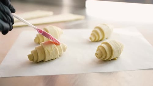 Chef Applies Egg Wash to Croissant Dough Closeup