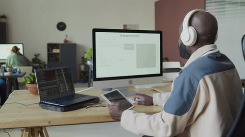 Schwarzer männlicher IT-Ingenieur, der Softwarecode schreibt und auf dem Desktop-Computer überprüft