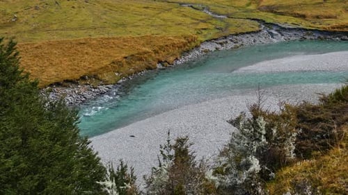 clear blue river flowing through grassy mountain valley