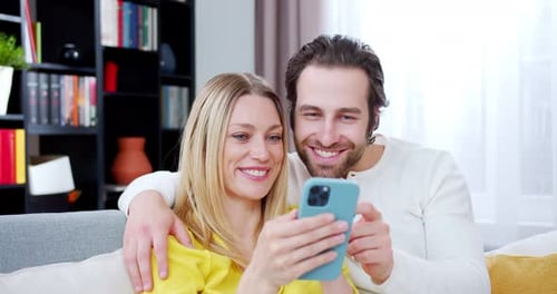 Couple Using Smartphone Together on Couch Indoors
