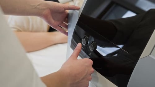 Woman Beautician Adjusting Settings on Professional Beauty Device