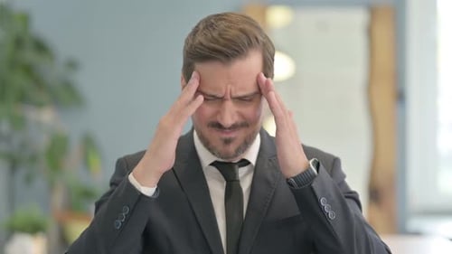 Man in Suit Suffering From Headache Indoors