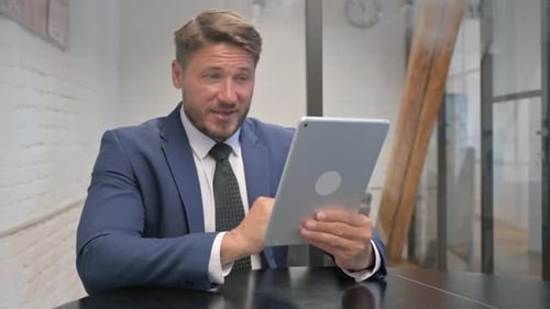 Man Talking on Tablet Video Call in Office