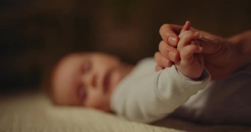 Loving touch: Mother holds infant baby's hands