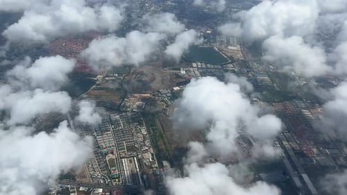 An aerial view of the clouds and cityscape below the clouds.