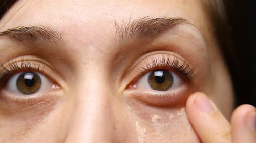 Frau trägt Concealer-Make-up unter ihren Augen auf.