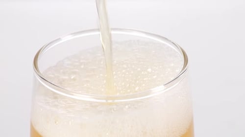 Close Up Of Beer Being Poured Into A Glass On The Light White Screen Background In The Studio