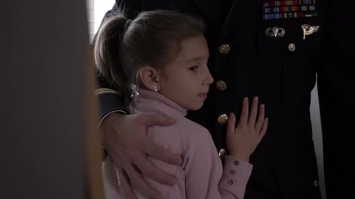 Little Girl Hugs a Soldier in Uniform
