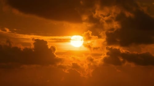 Zeitraffer eines dramatisch Sonnenaufgangs mit orangefarbenem Himmel an einem bewölkten Tag.