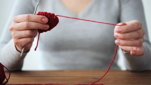 Woman Crocheting a Red Design at Home