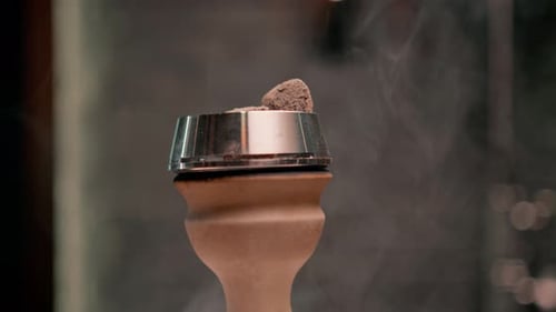Nahaufnahme einer Shisha-Schale mit brennenden Kohlen im Rauch im Hintergrund in der Loungebar Shisha-Rauchen
