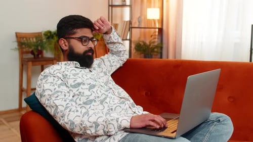 Man Relaxing on Couch While Using Laptop