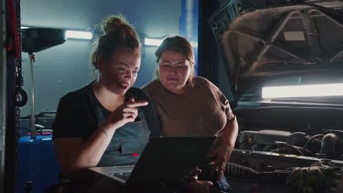 Mechanics Troubleshooting Engine Issues While Reviewing Data on Laptop