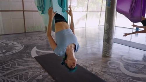Young Asian Woman is Training in Fabric Hammock in Studio Dressed in Stylish Sportswear