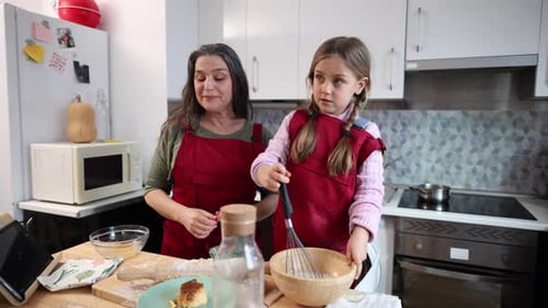 Großmutter und Enkelin kochen zu Hause in der Küche und bereiten Kuchen zu