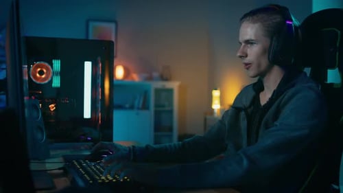 Excited young man gaming at desk in room