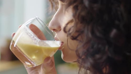 Woman Drinks Healthy Beverage Indoors Close Up