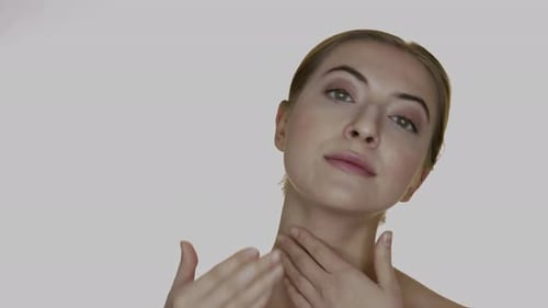Neck care. A young woman rubs the cream into the skin of her neck massaging it. A therapy for the sk