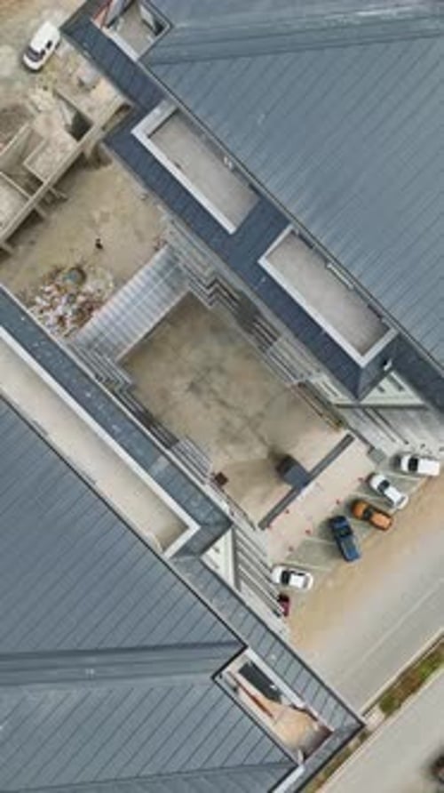 Los constructores de vídeo verticales trabajan en el acristalamiento de los balcones y en los detalles de la fachada mientras las máquinas colocan los cimientos