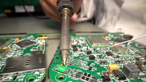 Engineer Solders Circuit Board And Microchip