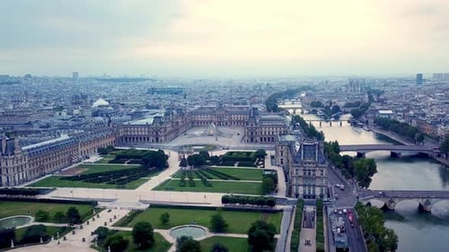 Drone se movendo para a direita, no alto, de frente para o museu do Louvre, pirâmide e rio Sena