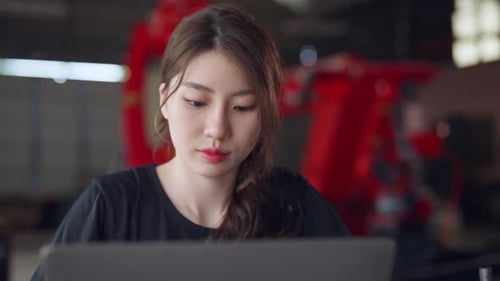 Focused female engineer working on her laptop in a factory