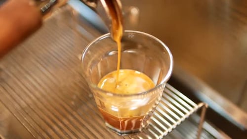 Close Up Footage Of Coffee Extraction Dripping Down From Coffee Machine To Shot Glass
