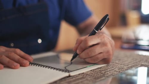 Man Drawing in Sketchbook with Pen