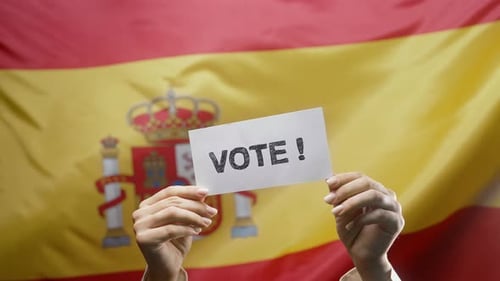 Mujer sostiene un cartel de título con texto: voto, bandera española, antecedentes, elecciones generales en España
