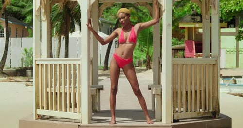 A black girl basks in the beauty of a Caribbean beach, dressed in a vibrant red bikini.