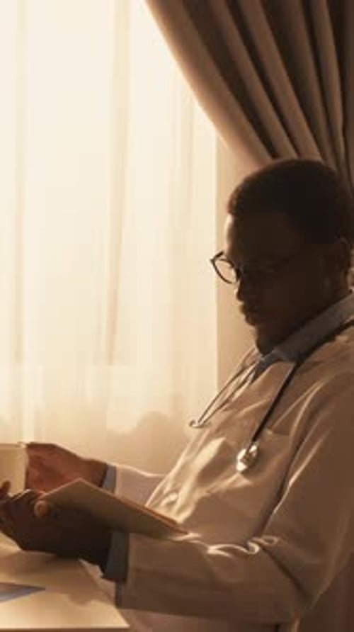Doctor Drinks Coffee, Reads Book by Sunny Window