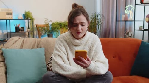 Woman Using Phone on Couch, Looking Upset