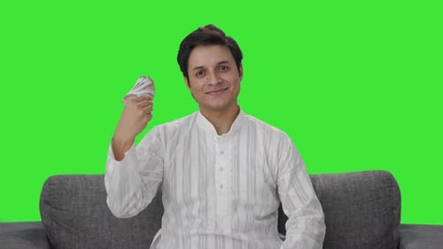 Happy Indian man using money as fan Green screen