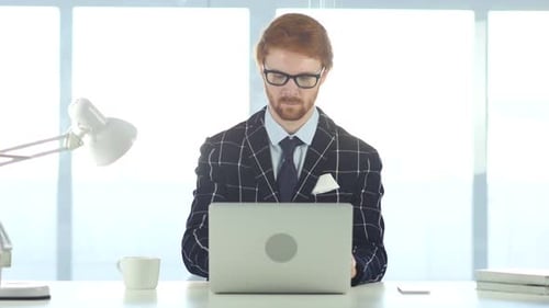 Redhead Man Working On Laptop in Office