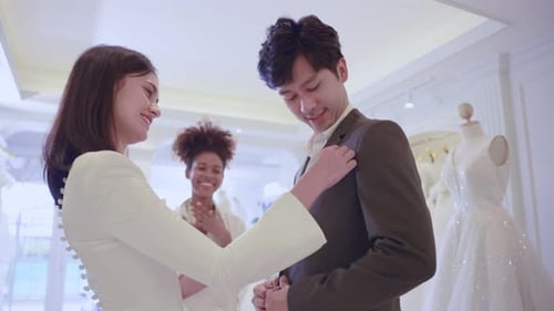Asian beautiful bride trying on wedding gown with her fiance in studio.