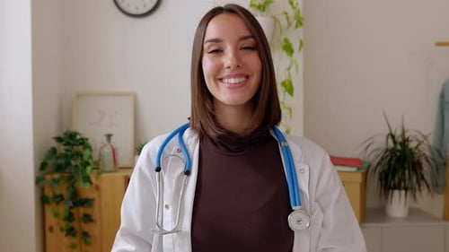 Portrait of Young Female Doctor Smile at Camera Sitting at Office Desk