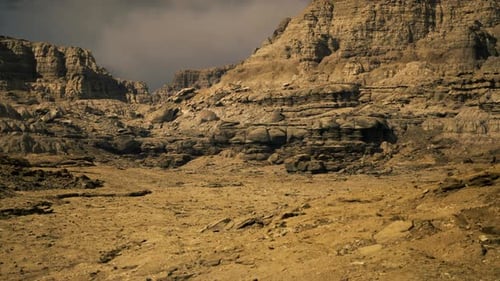 Rocky Desert Landscape with Rugged Formations and Dry Terrain Under Cloudy Sky