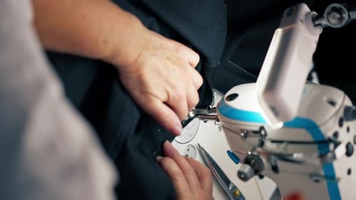 Vertikales Video, Nahaufnahme in einer Nähwerkstatt auf einer Maschine, die alte Schneiderin schneidet auf einer