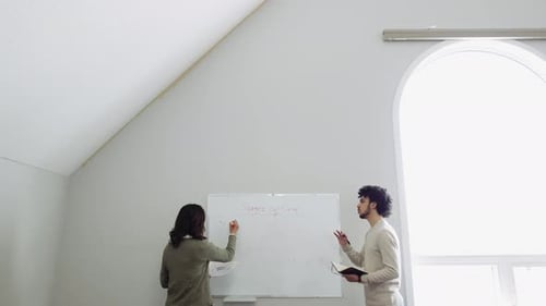 Support group writes stages of grief on whiteboard in bright community center