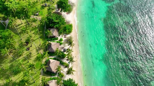 A tropical island with resorts surrounded by clear waters. Drone view.