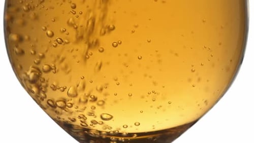 Amber Liquid Poured into Glass, Creating Bubbles